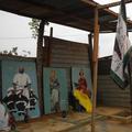 A small wooden shelter with three paintings of royalty underneath, man with flag in foreground